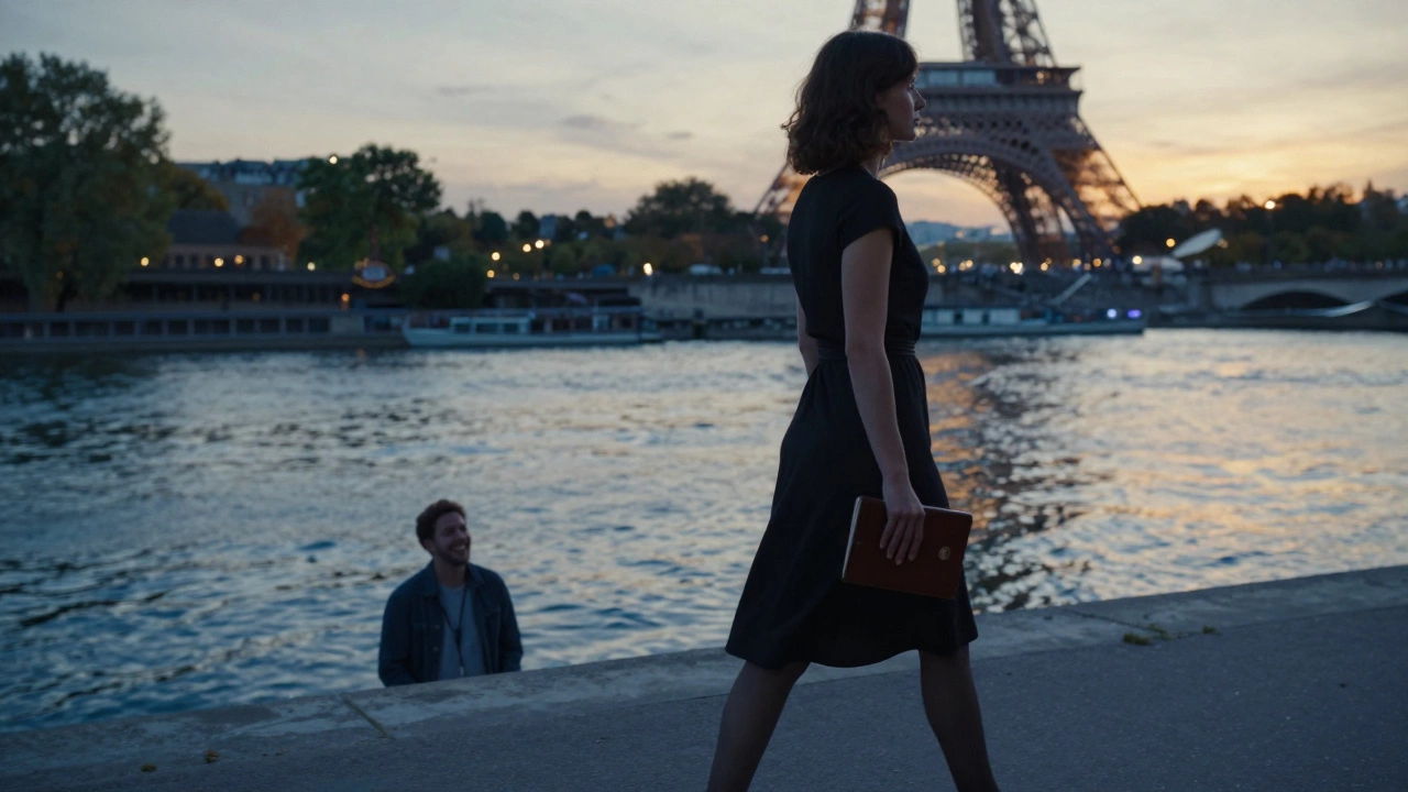A woman walks alone along the Seine at sunset, her reflection visible in the water as the Eiffel Tower glows behind her.